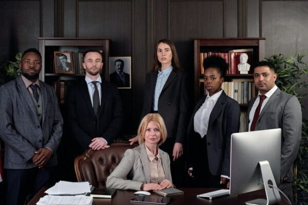 Businesswoman sitting at desk with business people around her