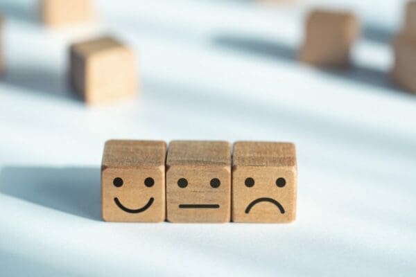 Three wooden cubes with happy, neutral and sad faces