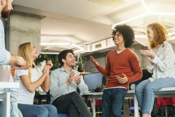 Group of colleagues having a conversation in the office and looking happy showing great interpersonal skills