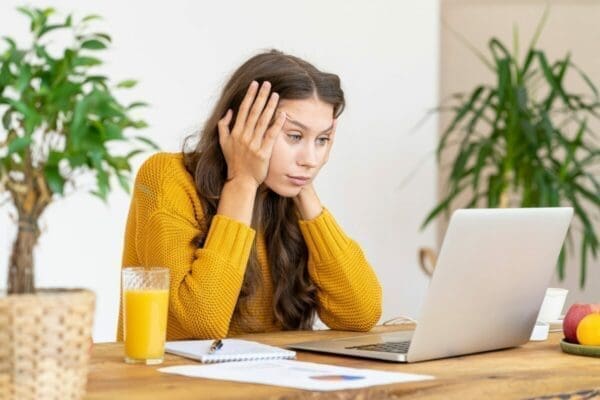 Businesswoman at desk with head in hands, stressed by emails