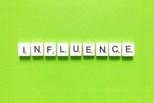 Influence spelled with word scramble tiles on green background