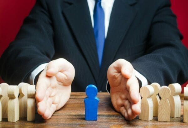 Businessman with hands around a wooden blue figure