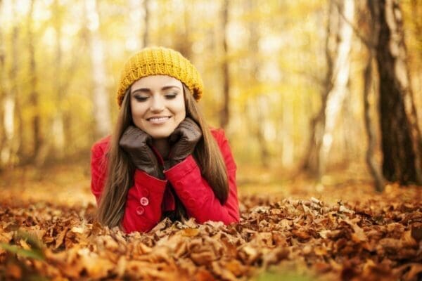 Smiling happy woman relaxing in the park at autumn practising mindfulness