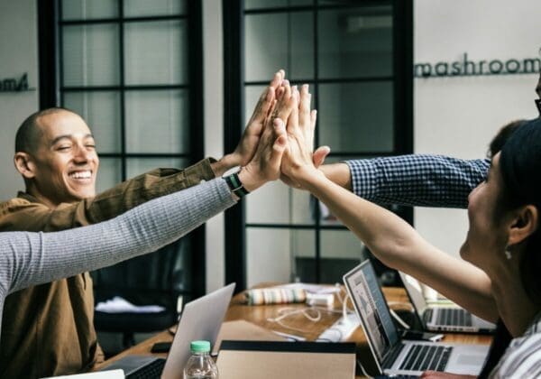 Team of business people high-fiving on a table are collaborating