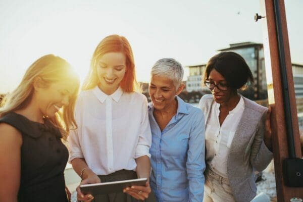 Group of female colleagues in a team looking at a tablet 