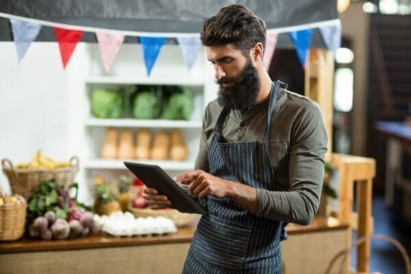 Grocery vendor using a digital tablet to analyse product placement on the shelf