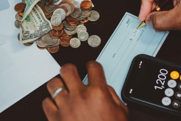 Hand writing check with coins and calculator on the table