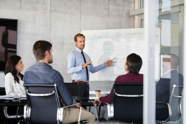 Businessman giving presentation on a whiteboard with colleagues