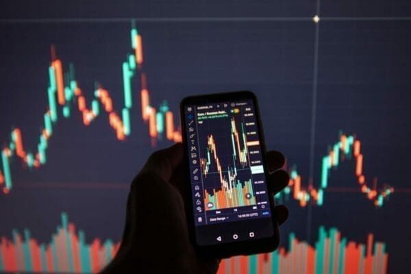 Hands holding phone showing market data