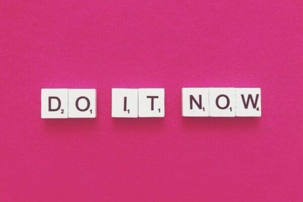 Do it now spelled with scrabble tiles on pink background to stop proacrastinating