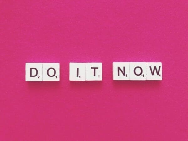 Do it now spelled with scrabble tiles on pink background to stop proacrastinating