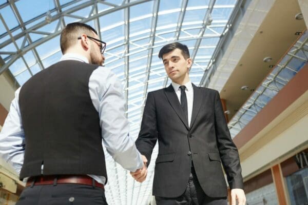 2 businessmen shaking hands inside a building