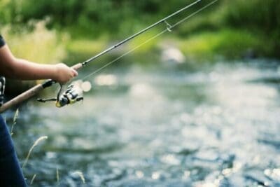 Person holding a fishing pole over a river