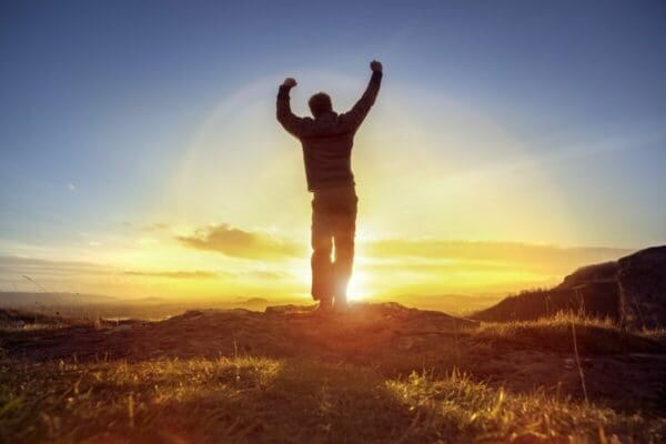 Happy man celebrating winning success against sunset