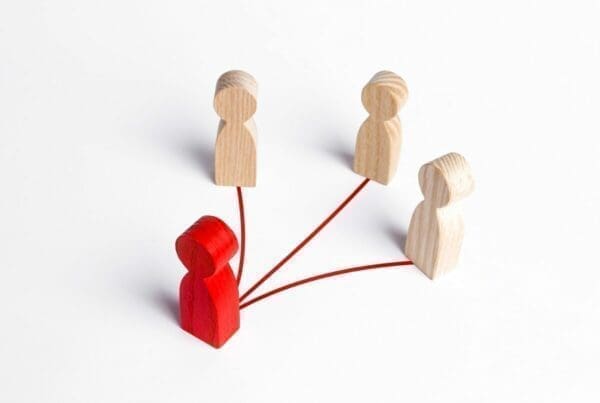 Red wooden leader figure leading three follower figures