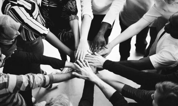 Black and white picture of many hands in a circle from diverse businesspeople