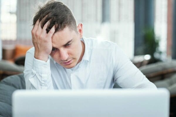 Stressed businessman looking at his laptop ashe works from home