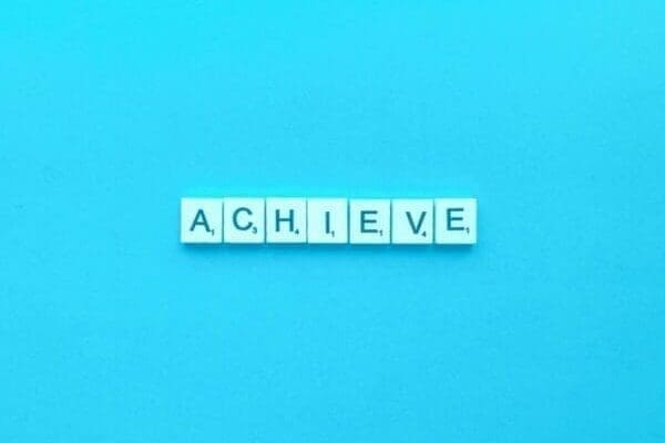 Achieve spelt out in Scrabble tiles and blue background