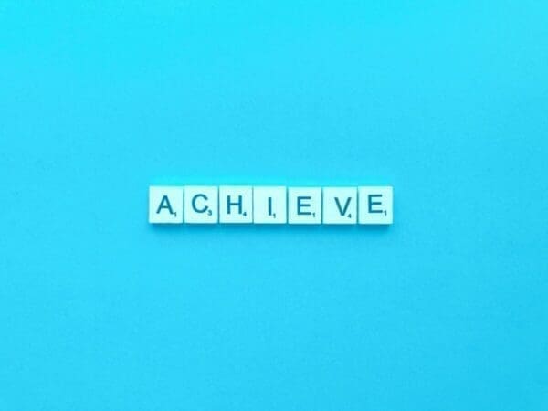 Achieve spelled out in word Scrabble cubed on a blue background