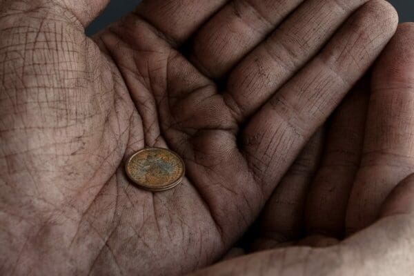 Single coin in a pair of dirty hands from a pleader beggar