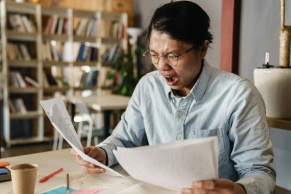 Shocked man looking at negotiation paperwork about Buyer Tactics in Negotiation