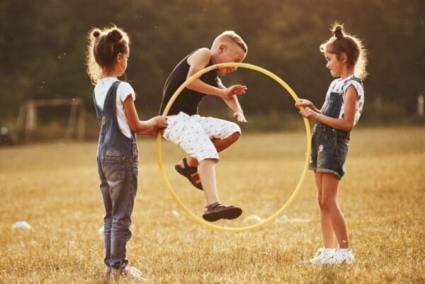 Kids in a field jumping through hoop