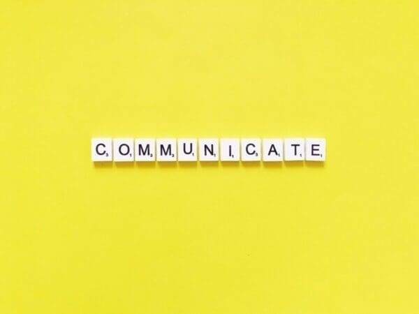 Communicate spelt out in scrabble tiles on yellow background