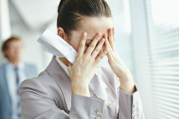 Businesswoman with hands over face is stressed