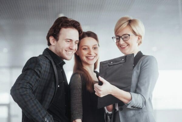 Smiling female boss uses a clipboard as she talks to coworkers about human resource goals and objectives