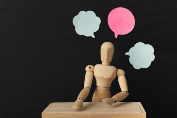 Wooden man mannequin with blank speech bubbles for communication
