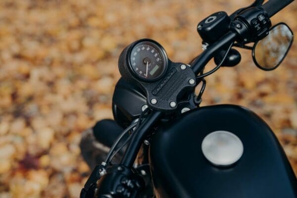 Black motorbike on ground covered with orange foliage in autumn park