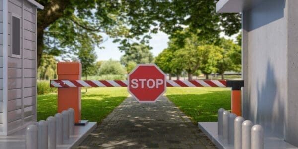 Red stop sign on a closed gate with a nature background