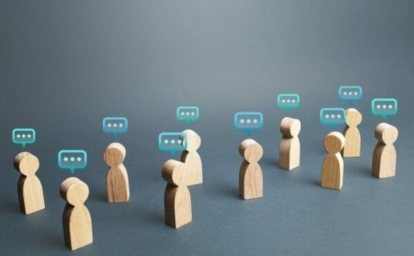 Wooden human figures with speech bubbles representing communication