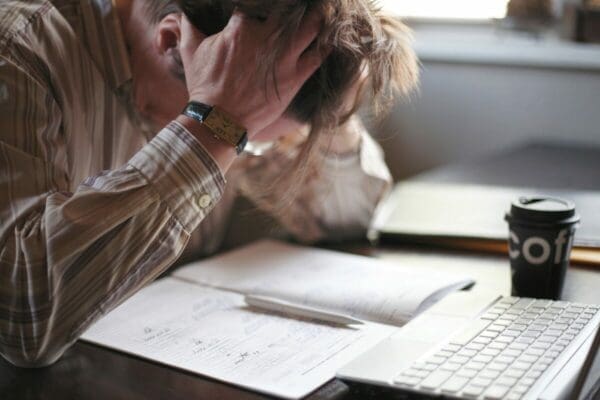 Stressed man in front of keyboard and paperwork