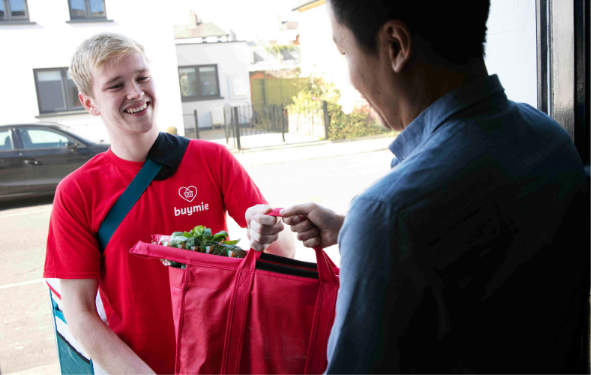 Happy Buymie delivery driver delivering red bag