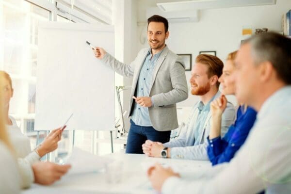 Businessman making a presentation to workers in a white lit clean office