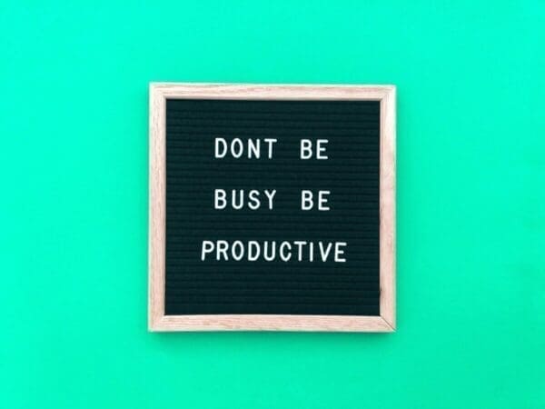 Productivity and busy quote on a felt board on a green background. 
