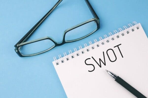 SWOT written on a notepad with a pen and blue background