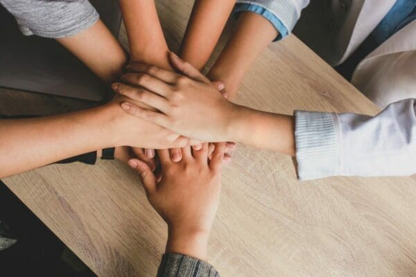 Office team with their hands in the centre showing teamwork