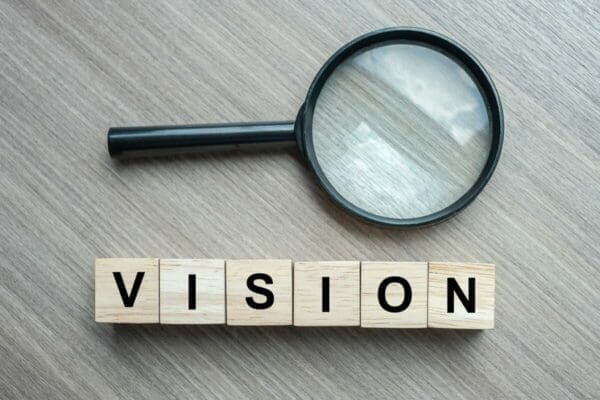 Magnifying glass with word 'Vision' below in wooden blocks