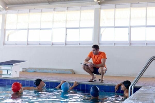 Male coach teaching swimmers at the pool