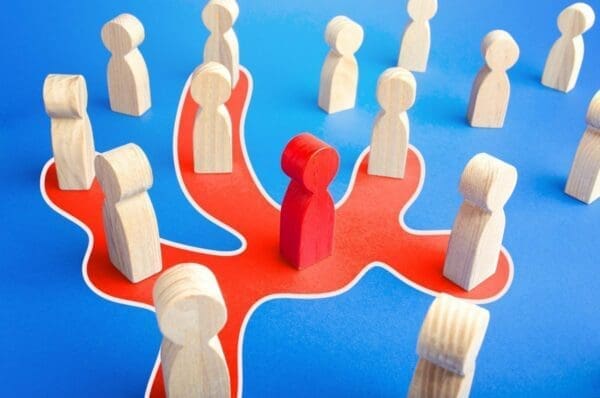 Read leader figure communicating with other wooden figures on blue background
