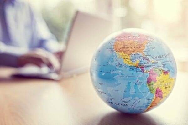 A small globe on the table with businessman in background