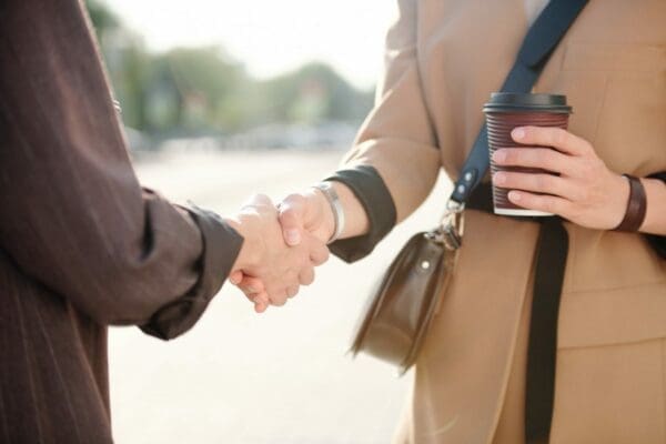 Two young successful female business partners shaking hands after negotiating