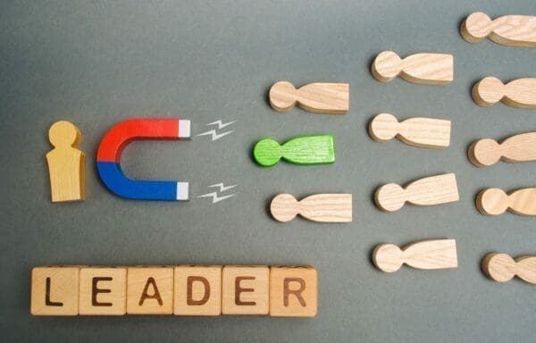 Leader spelled with wooden cubes and a leader magnet attracting follower figures