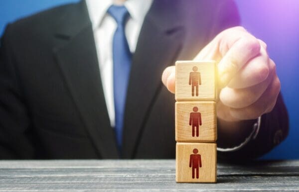 Businessman stacking 3 wooden blocks with figures on them