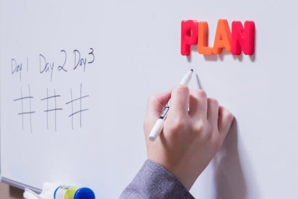 Plan spelled with yellow and orange letter magnets on a whiteboard