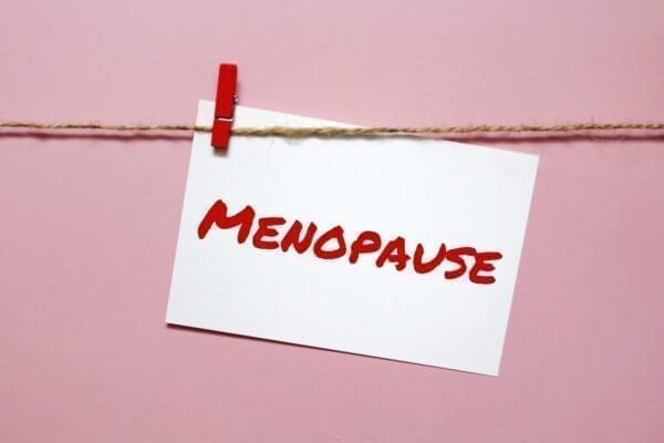 Menopause written in red on a note pinned to a line with pink backgorund