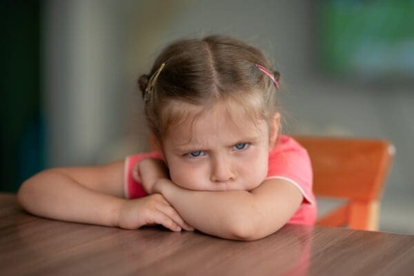 Angry little girl seated at a table