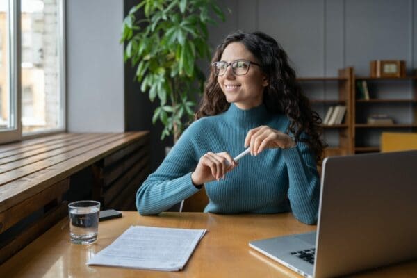 Happy female employee at her work desk displays wellbeing